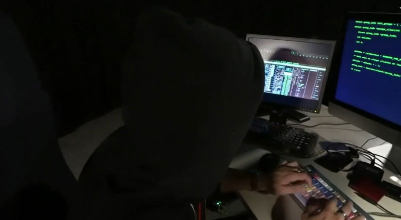 Una persona treballant amb ordinadors en la foscor