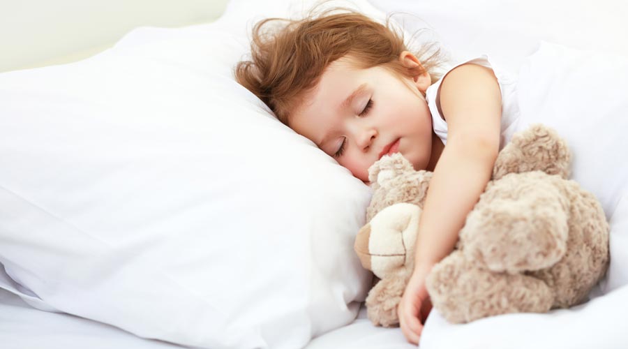 Un nen dormint amb el seu peluix