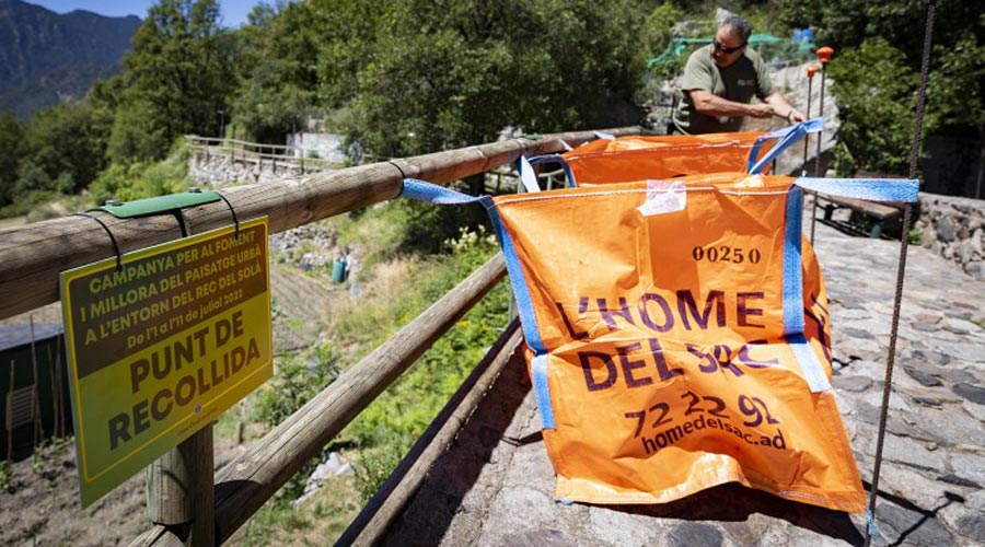 Un home depositant voluminosos en un sac al rec del Solà