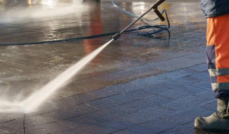 Un home netejant un carrer amb aigua