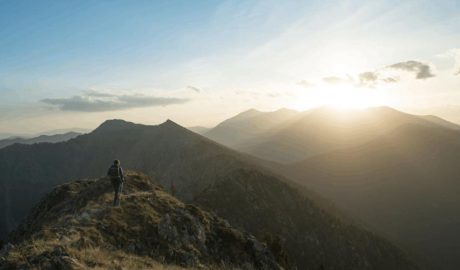 Home passejant per la muntanya amb el sol al davant