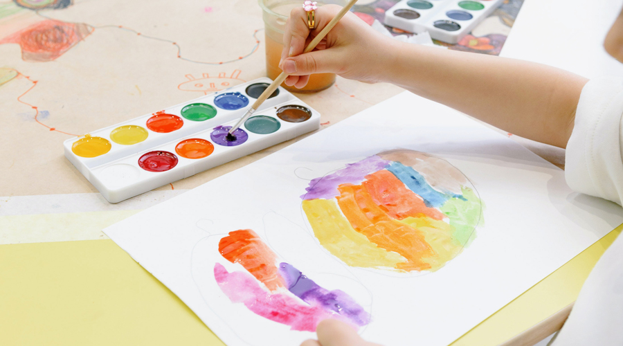 Una nena pintant amb aquarel·les