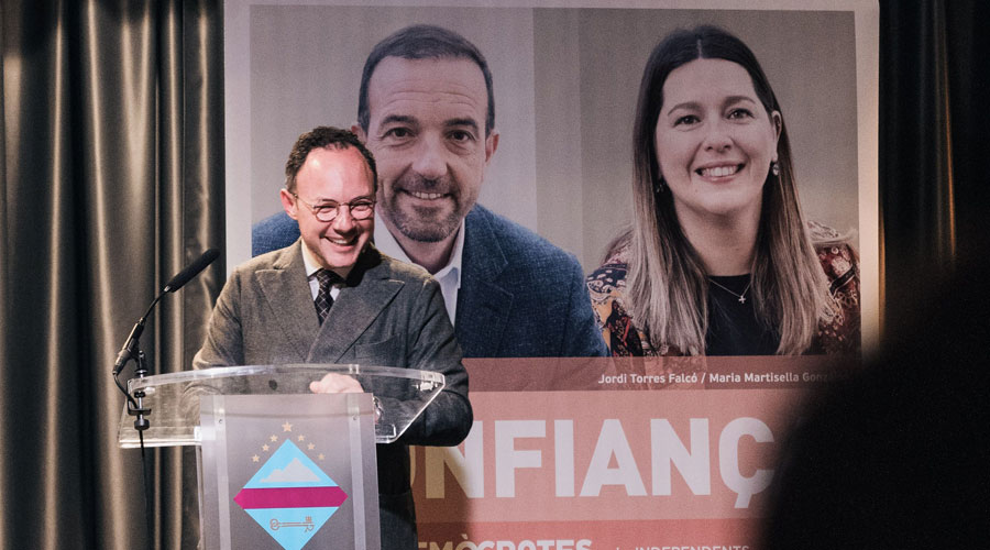 Xavier Espot en la reunió de poble, a Encamp, amb el cartell de fons dels candidats parroquials de DA + UP (Demòcrates)