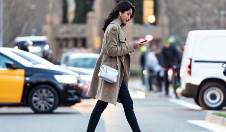 Una noia utilitzant el mòbil mentre creua un pas de vianants