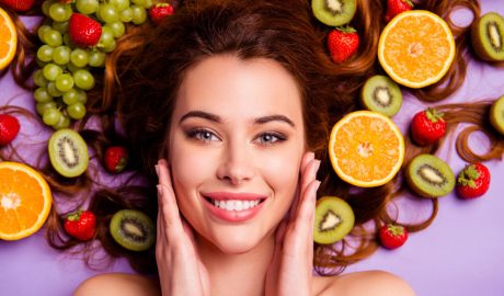 Una dona jove envoltada d'una gran varietat de fruita