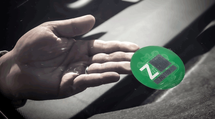 Un persona col·locant el distintiu ambiental en un vehicle (SFGA)