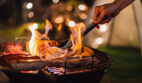 Un home fent una barbacoa amb un excés de flama