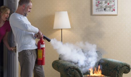 Un home apagant amb l'extintor un petit incendi a la llar