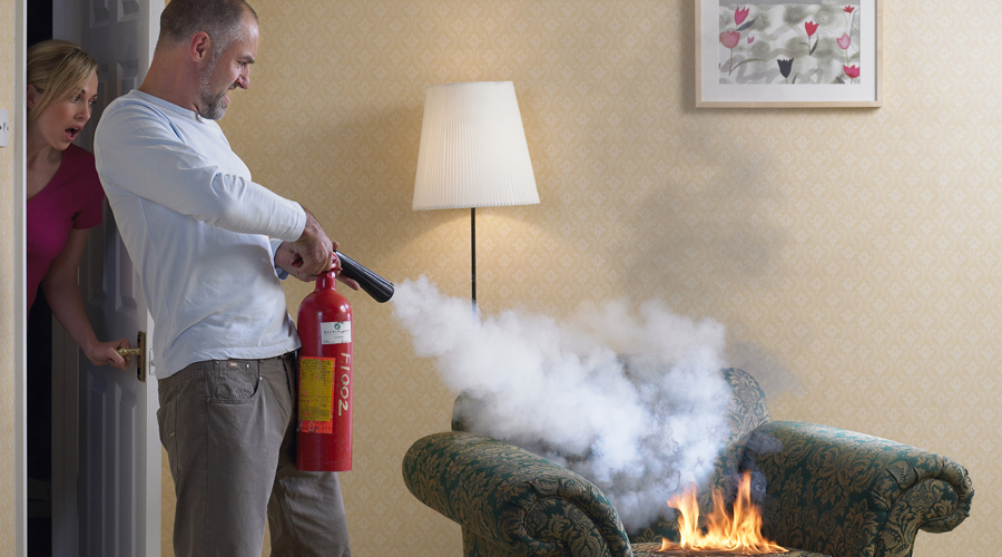 Un home apagant amb l'extintor un petit incendi a la llar (Getty images)