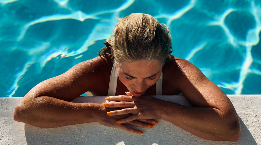 Una dona amb les ungles taronges banyant-se a la piscina a l'estiu
