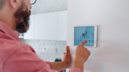 Un home regulant la calefacció de la casa