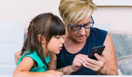 Una àvia amb la seva neta manipulant un telèfon mòbil