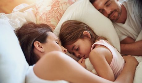 Una nena dormint amb els seus pares