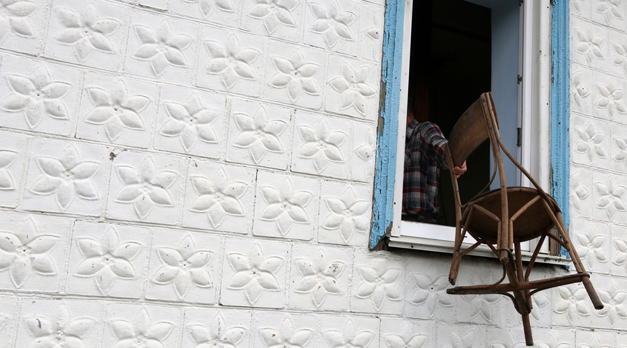 Un home fent la intenció de llençar una cadira per la finestra