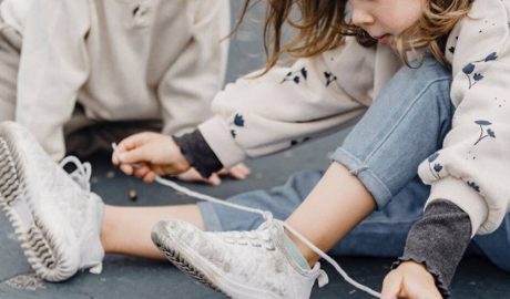 Una nena intentant lligar-se els cordons de les bambes