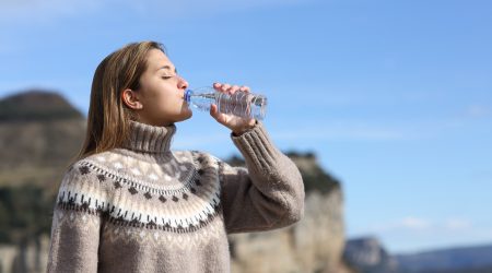 Una dona bevent d'una ampolla de plàstic amb aigua