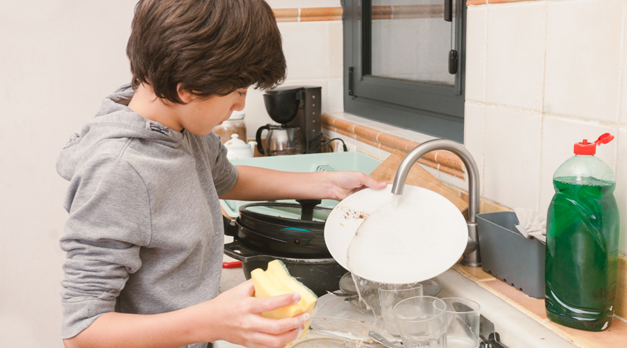 Un nen rentant els plats a casa